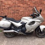 Silver Triumph motorcycle with slight paintwork damage.